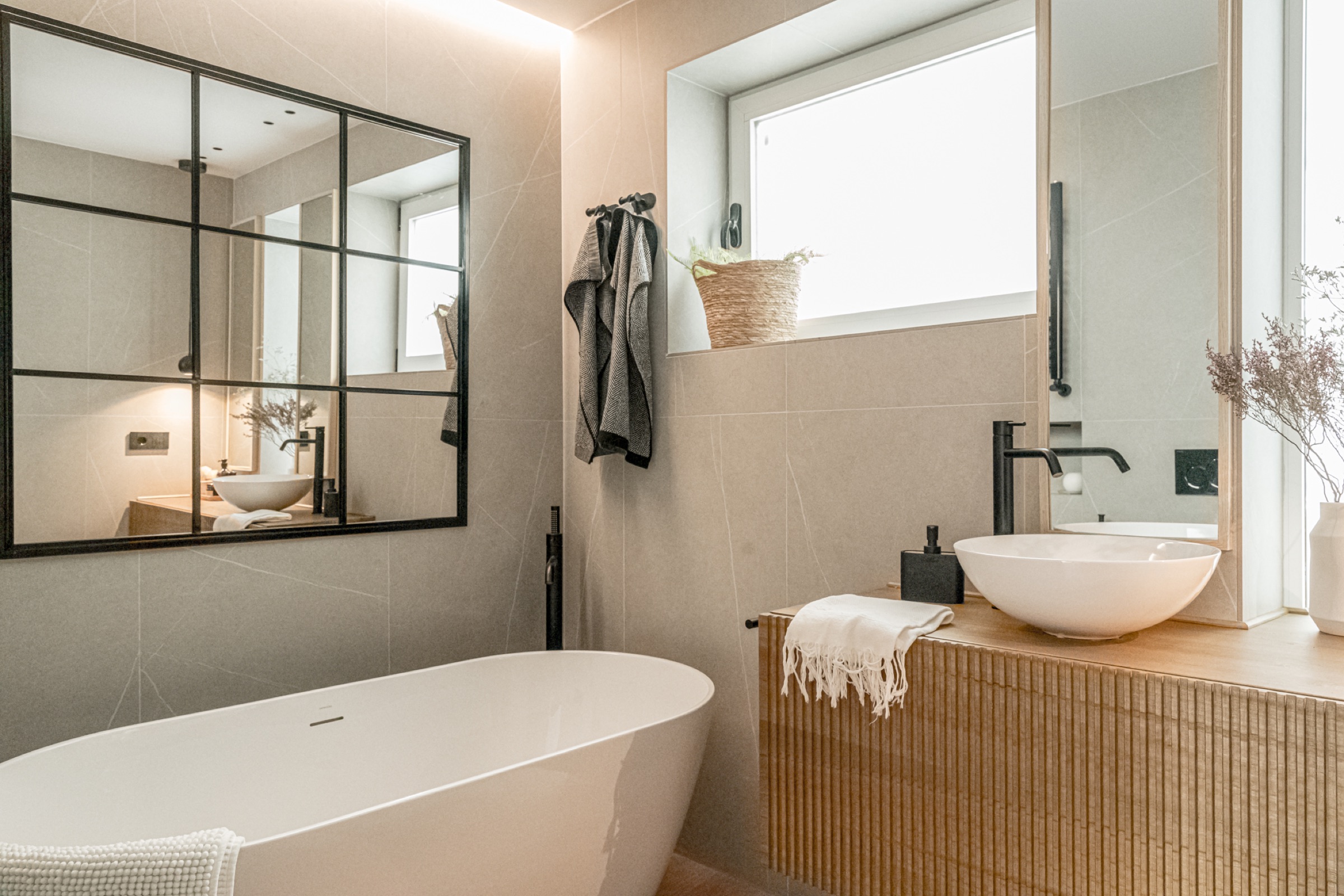 Baño con bañera exenta, mueble de listones de madera y espejo tipo industrial